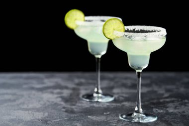 Margarita kokteylini limon ve tuzlu siyah bir masada, seçici bir odak noktası ile tazeliyorum..