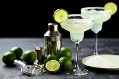Dilimlenmiş limonlu margarita kokteyli ve tüm limonlar siyah bir masada..