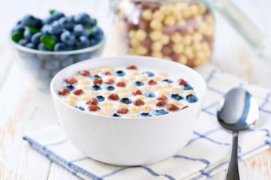 Ccorn topları, çikolatalı mısır topları ve açık mutfak masasında yaban mersinli çocuklar için kahvaltı, seçici odaklanma. Kahvaltıda meyve ve sütle birlikte iki aromalı sağlıklı mısır topları. İki aromalı mısır köftesi ve süt, sabah kahvaltısı..