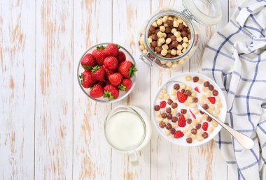Mısır topları, çikolatalı mısır topları ve açık mutfak masasında çilekli çocuklar için hızlı bir kahvaltı. Kahvaltıda meyve ve süt ile sağlıklı mısır topları..