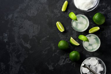 Siyah bir masada limon parçalarıyla margarita kokteyllerinin üst görüntüsü, metin için boşluk kopyala.