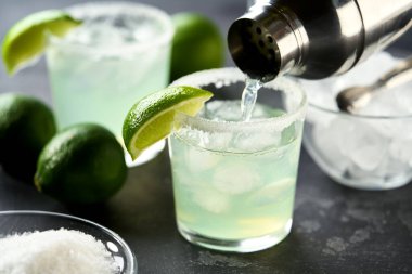 Margarita kokteyli bardaktan bardağa, limona, tuzluğa, seçici odak noktasına dökülür..