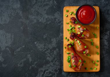 Siyah bir masada soslu ızgara tavuk budu..