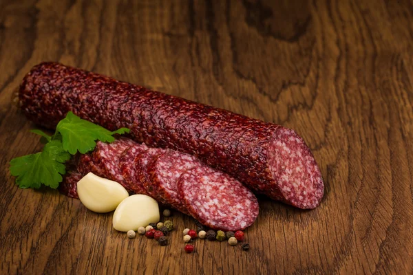 Välsmakande salami korv och kryddor på trä bakgrund — Stockfoto