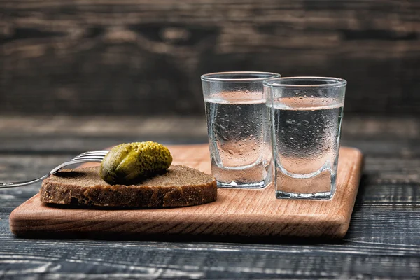 Shot glasses with vodka and pickled cucumbers on a fork — Stock Photo, Image