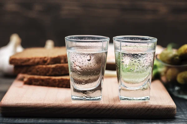 Русская водка в маленьком стакане с черным хлебом и огурцами — стоковое фото