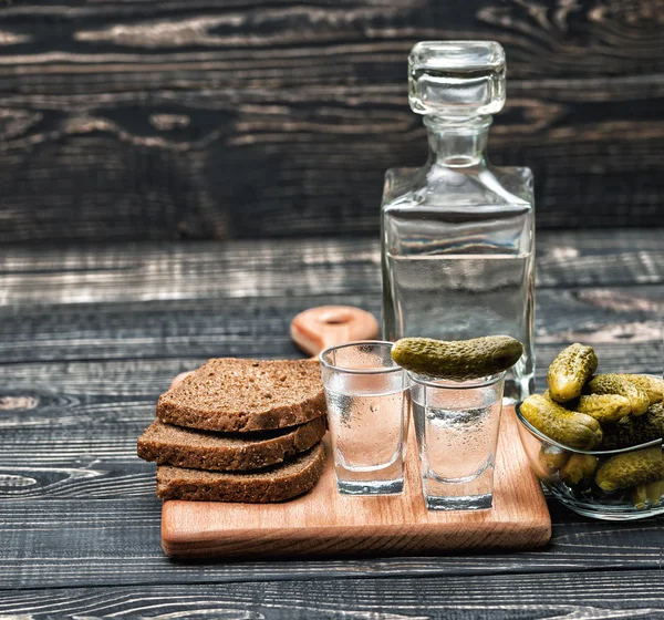 Saltgurka i en liten burk och två vodka shots — Stockfoto