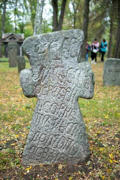 Een versleten zandsteen graf marker in de schaduw op een zeer heldere dag. Er is geen tekst op de steen te zien, maar er zit wel mos aan de bovenkant. Grafsteen en graven in een oud kerkhof. getemperd — Stockfoto