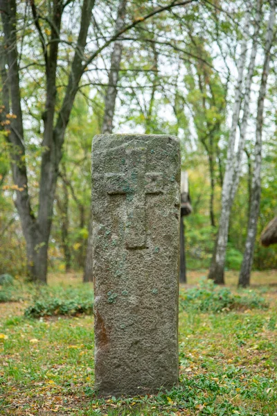 Noszony piaskowcowy marker grobowy w cieniu w bardzo jasny dzień. Na kamieniu nie ma widocznego tekstu, ale na górze jest mech. Kamień nagrobny i groby na starożytnym cmentarzu kościelnym. stonowana — Zdjęcie stockowe