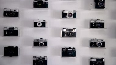 Beyaz duvarda büyük bir eski kamera koleksiyonu var. çeşitli eski fotoğraf makineleri