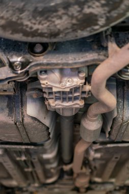 Araba tamiri, tamirat, tamirat, telefoto. Araba bakım atölyesi. Garaj dükkanında arabanın altında tamir için kaldırılan şasi arabası. Dikey fotoğraf. ses tonlu.