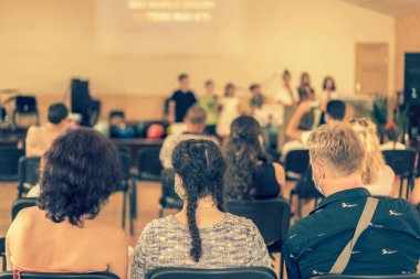 İlkokulda çocuk tatili. Sahnedeki çocuklar ailelerinin önünde gösteri yapıyorlar. Görünmez çocuğun görüntüsü okulda sahnede, arka plan kullanımı için. Bulanık. ses tonlu.