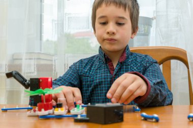 Elektrikli bir inşaatçıyı oynayan çocuk. Çocuk entellektüel oyuncaklar tarafından oynanır. Mavi gömlekli bir çocuk elektronik ustası. Çocukların erken gelişimi kavramı. ses tonlu.