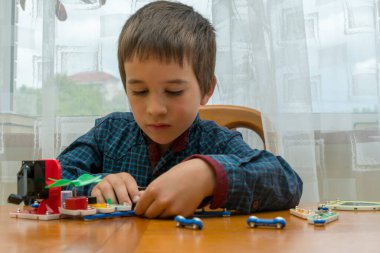 Elektrikli bir inşaatçıyı oynayan çocuk. Çocuk entellektüel oyuncaklar tarafından oynanır. Mavi gömlekli bir çocuk elektronik ustası. Çocukların erken gelişim kavramı.