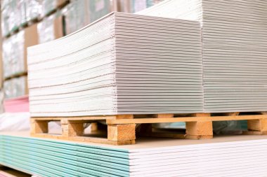 Yapı deposunda alçıpan levhalı paleti var. Beyaz alçı taşı panelleri, alçı levhalar ya da alçı levhalar yığılıyor. Pakette alçı taşı var..