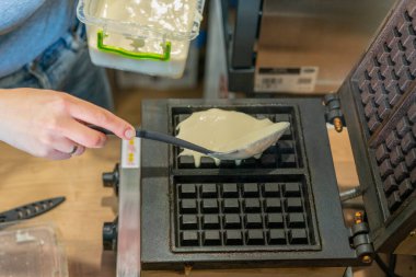 Mutfakta gözleme ızgarası var. Ev yapımı waffle hazırlamak, hamur dökmek. Çift waffle makinesinde ev yapımı waffle hazırlıyorum. Seçici odaklanma. ses tonlu.