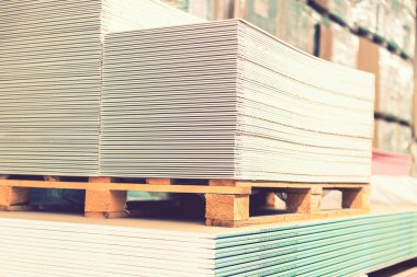 Yapı deposunda alçıpan levhalı paleti var. Beyaz alçı taşı panelleri, alçı levhalar ya da alçı levhalar yığılıyor. Alçıtaşı alçıtaşı pakette. ses tonlu.