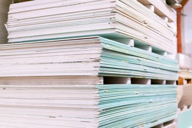 Yapı deposunda alçıpan levhalı paleti var. Beyaz alçı taşı panelleri, alçı levhalar ya da alçı levhalar yığılıyor. Pakette alçı taşı var..