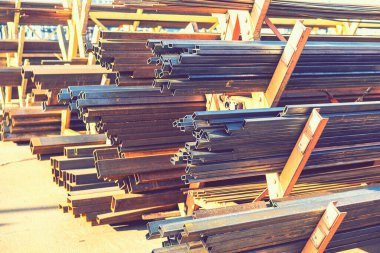 Rafta çelik borular ve metal kirişler var. Metal borular, profiller, çubuklar, köşeler, raylar, metal ürünlerin seçimi. Metal atölyesi. ses tonlu