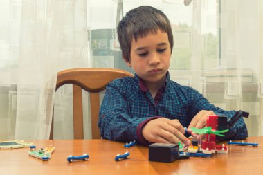 Elektrikli bir inşaatçıyı oynayan çocuk. Çocuk entellektüel oyuncaklar tarafından oynanır. Mavi gömlekli bir çocuk elektronik ustası. Çocukların erken gelişimi kavramı. ses tonlu