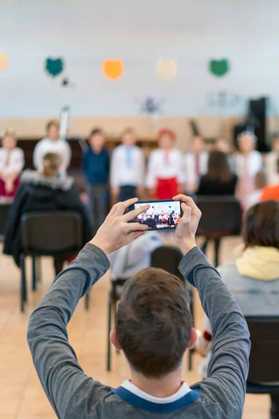 Anaokulunda ya da okulda çocukların performansında ebeveynler. Çocuklar sahneye. Birçok ebeveyn tatilde çocukların koridorda performansını izliyor. ses tonlu — Stok fotoğraf