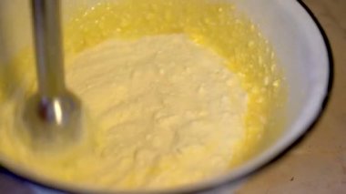 Hamur, blender ya da mikserle yenir. Turta ya da kurabiye yapmak için. Ev yapımı pişirme. Turta güveci için süzme peynir hamuru hazırlıyorum. Beyaz kasede süzme peynir, tereyağı, yumurta ve şeker. Yakın plan.