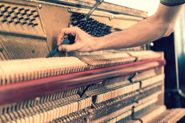Piyano akort işlemi. Büyük piyanoda çalışan el ve akort aletlerinin yakın çekimi. Akort sırasında Upright Piano 'nun detaylı görüntüsü. ses tonlu.