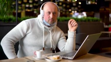 Adam kulaklıkla müzik dinliyor. Kafede oturan akıllı telefona bakıyor. Yemek molasında kulaklıkla müzik dinleyen bir adam. Eğlence, teknoloji ve yaşam tarzı konsepti