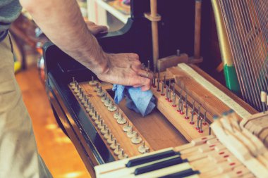 Setting up an old piano. The master repairs an old piano. Deep cleaning the piano. Hands of professional worker repairing and tuning an old piano. toned. clipart