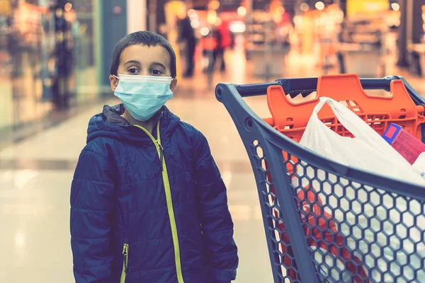 Boy wears protected mask in store. Shopping time during coronavirus outbreak. Boy in a medical mask. Shopping with kids during virus outbreak. Boy in face mask in supermarket. toned
