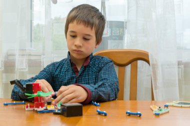 Elektrikli bir inşaatçıyı oynayan çocuk. Çocuk entellektüel oyuncaklar tarafından oynanır. Mavi gömlekli bir çocuk elektronik ustası. Çocukların erken gelişimi kavramı. ses tonlu