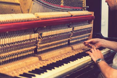 Piyano akort işlemi. Büyük piyanoda çalışan el ve akort aletlerinin yakın çekimi. Akort sırasında Upright Piano 'nun detaylı görüntüsü. ses tonlu