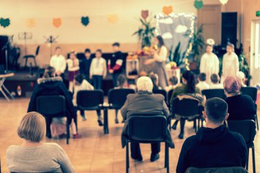 Anaokulunda ya da okulda çocukların performansında ebeveynler. Çocuklar sahneye. Birçok ebeveyn, Noel tatili boyunca çocukların koridorda performanslarını izliyor. ses tonlu