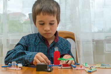 Elektrikli bir inşaatçıyı oynayan çocuk. Çocuk entellektüel oyuncaklar tarafından oynanır. Mavi gömlekli bir çocuk elektronik ustası. Çocukların erken gelişim kavramı