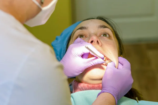 Male dentists examining and working on young female patient.Dentists office. Real woman in a chair at the dentist. toned