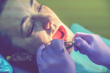 Erkek dişçiler genç bayan hasta üzerinde çalışıyor. Dişçi muayenehanesi. Dişçide sandalyede oturan gerçek bir kadın. ses tonlu