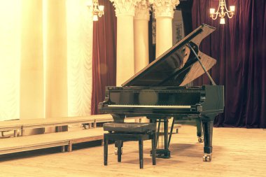 Konser Salonundaki Grand Piano. Piyano boş sahnede duruyor. Tahta bir konser sahnesinde siyah piyanoyu tabureyle açtı. ses tonlu