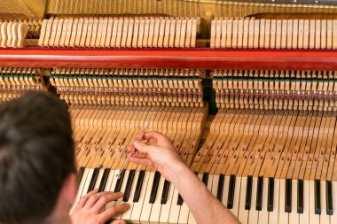 Piyano akort işlemi. Büyük piyanoda çalışan el ve akort aletlerinin yakın çekimi. Akort sırasında Upright Piano 'nun detaylı görüntüsü. ses tonlu