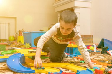 Yakışıklı çocuk yerde araba parkuruyla oynuyor. Çocuk içeride oyuncaklarla oynuyor. Evdeki çocuklar için etkinlikler. Yeni yürümeye başlayan çocuklar. Karantina sırasında anaokulundaki çocuk evde. ses tonlu