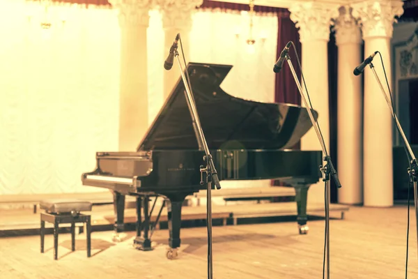 Grand Piano in Concert Hall. Piano standing on empty stage. opened black grand piano with stool on a wooden concert stage. toned