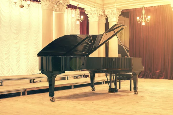 Grand Piano di Concert Hall. Piano berdiri di atas panggung kosong. membuka black grand piano dengan bangku di panggung konser kayu. Bernada Stok Lukisan  