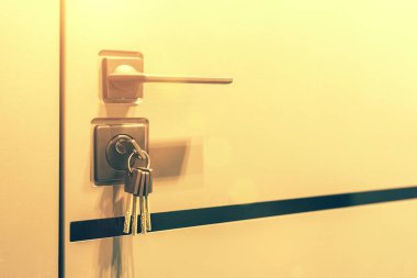 Anahtarlar kilide sıkışmış. Kapalı kapı kilitleri, emlak konsepti kapı kolu, anahtar yerleştirme ve beyaz kapının yatay metal düğmesini tut. ses tonlu