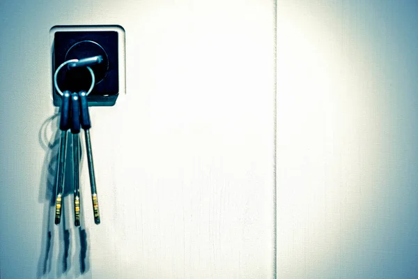 Llaves atascadas en una cerradura. primer plano Llaves de la cerradura de la puerta, manija de la puerta del concepto de bienes raíces, inserto de la llave y mantenga en botón metálico en la puerta blanca horizontal. tonificado — Foto de Stock