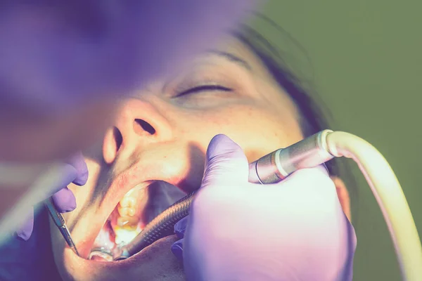 Mužští zubaři vyšetřují a pracují na mladé pacientce. Skutečná žena v křesle u zubaře. tónovaný — Stock fotografie