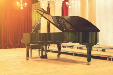 Konser Salonundaki Grand Piano. Piyano boş sahnede duruyor. Tahta bir konser sahnesinde siyah piyanoyu tabureyle açtı. ses tonlu