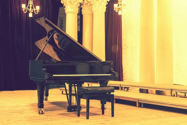 Grand Piano di Concert Hall. Piano berdiri di atas panggung kosong. membuka black grand piano dengan bangku di panggung konser kayu. Bernada Stok Foto Bebas Royalti