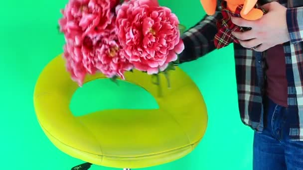 Man holding a stuffed toy and bouquet flowers on green background — Stock Video