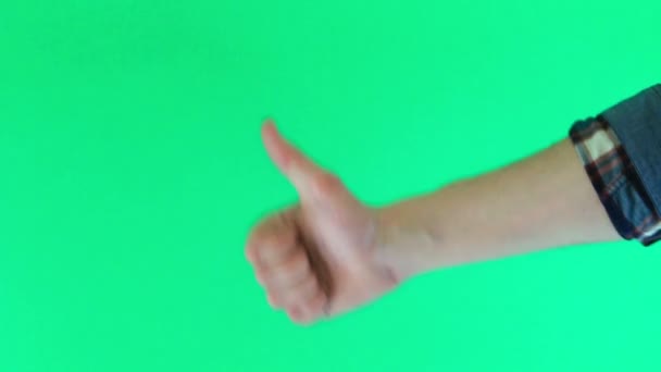 Close-up van mannenhand tonen duimen omhoog teken tegen een groene achtergrond — Stockvideo