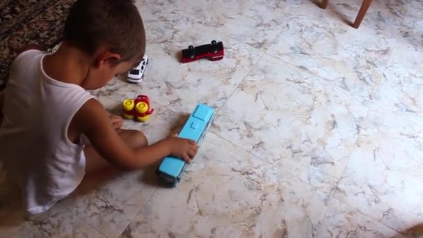 Petit garçon jouant des voitures jouets sur le sol — Video