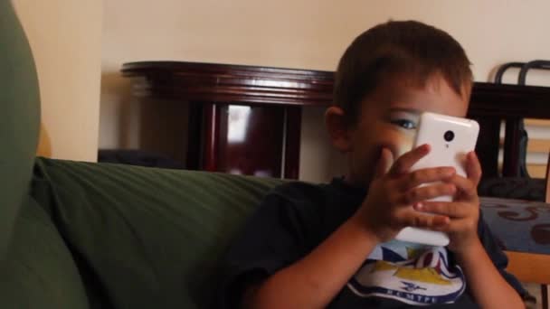 Little boy playing with mobile phone lying on the bed — Stock Video